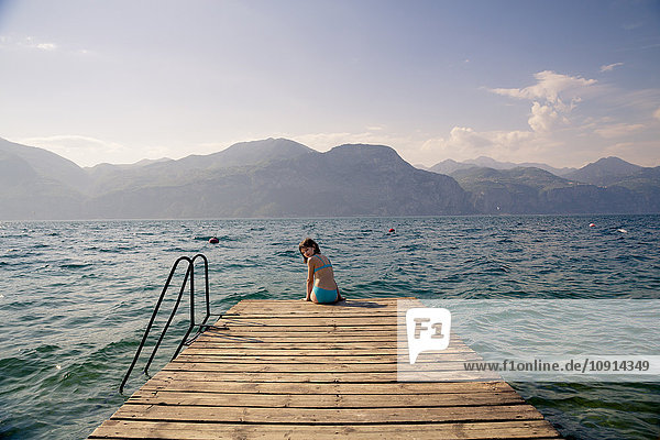 Italy  Brenzone  girl sitting on jetty