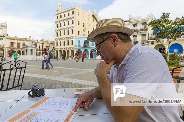 Cuba  Havana  Tourist sitting in pavement cafe  looking to menu card