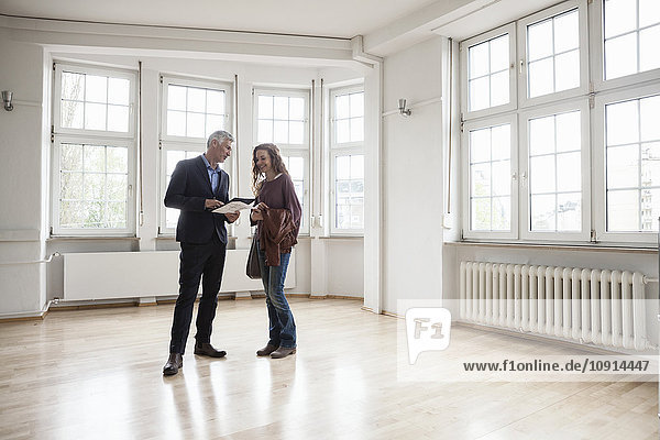 Immobilienmakler im Gespräch mit dem Kunden in einer leeren Wohnung