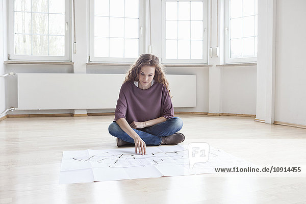 Woman looking at construction plan in empty apartment