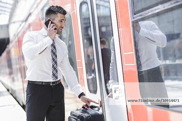 Businessman on cell phone getting into train