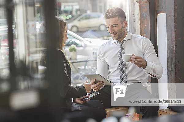 Businessman and businesswoman with digital tablet and smartphone in a cafe