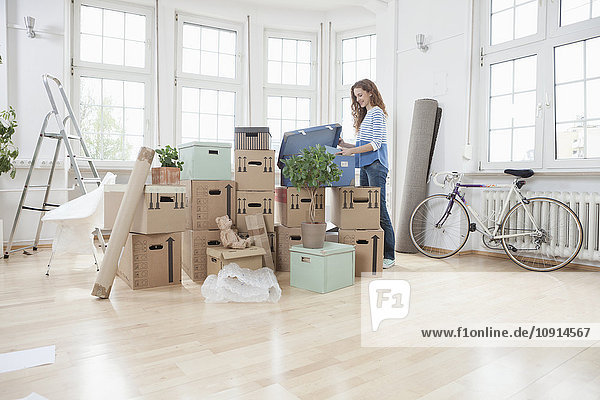 Woman in new apartment unpacking cardboard box