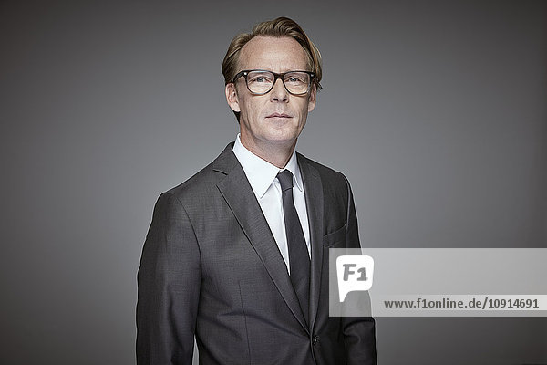 Portrait of serious businessman in front of grey background