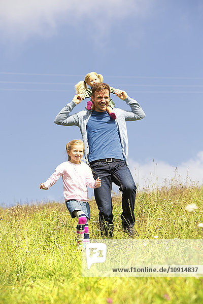 Glücklicher Vater und Tochter beim Spaziergang mit Puppe auf der Wiese