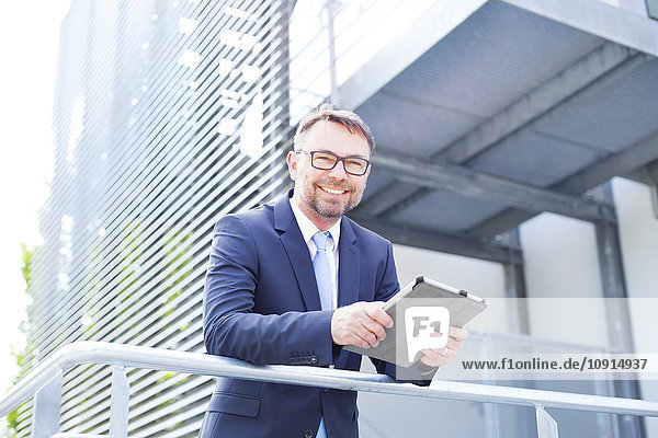 Smiling businessman with digital tablet outdoors