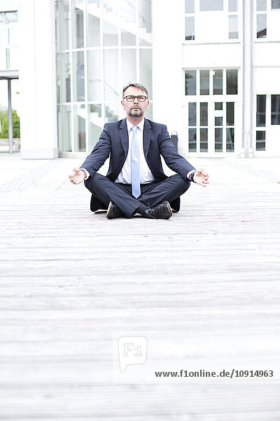 Geschäftsmann im Freien sitzend meditierend