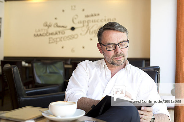 Porträt eines Geschäftsmannes  der in einem Café sitzt und etwas aufschreibt.