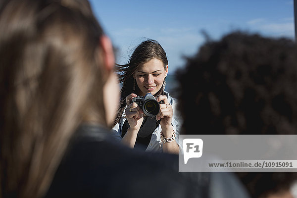 Young woman with camera photographing friends