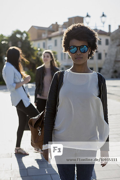 Young woman with sunglasses in the city with her friends