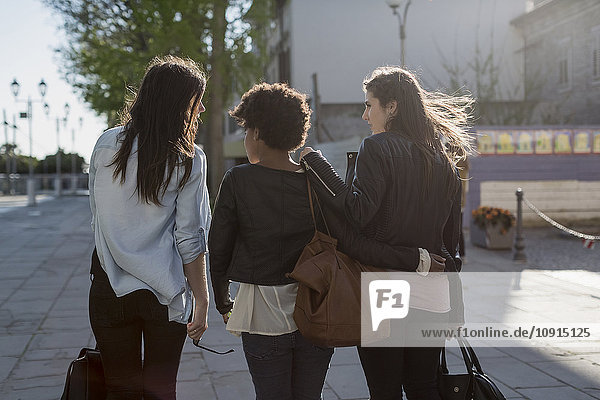 Drei junge Frauen  die in der Stadt spazieren gehen  Rückansicht