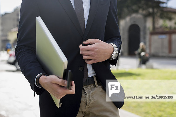 Businessman walking with laptop outdoors