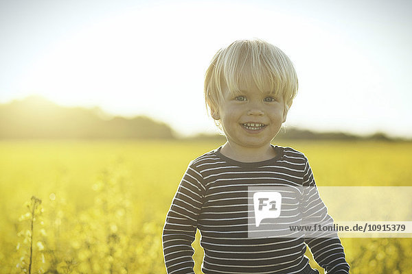 Porträt eines lächelnden Jungen im Rapsfeld