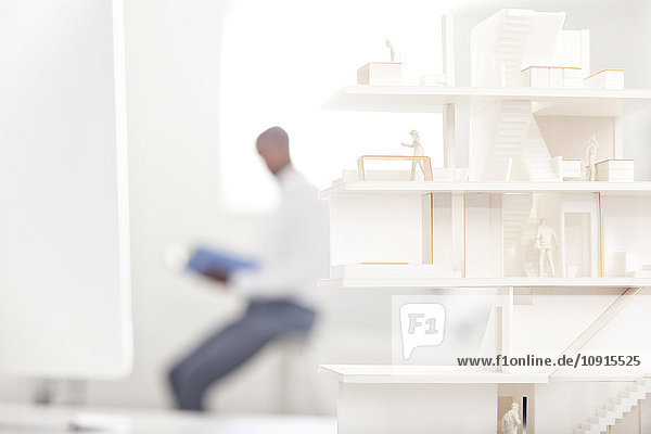 Architectural model on desk in an office with reading man in the background