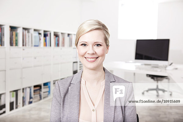 Porträt der lächelnden blonden Geschäftsfrau im Büro