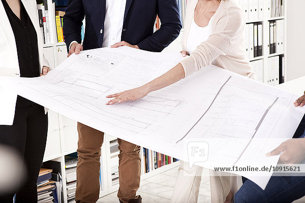 Four colleagues discussing construction plan in an office  partial view