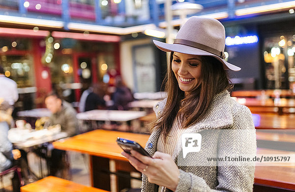 Porträt einer lächelnden jungen Frau die ihr Smartphone ansieht.