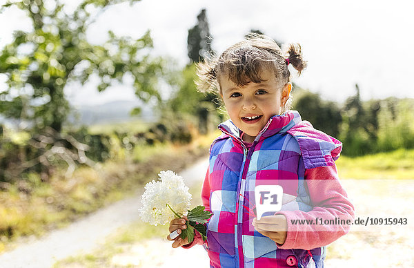 Porträt des lächelnden Mädchens mit Blume in der Hand