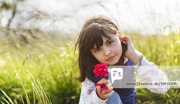 Portrait of little girl with red flower in nature
