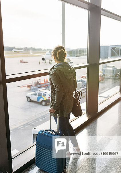 Spanien Asturien Frau die mit ihrem Koffer auf dem Flughafen wartet.