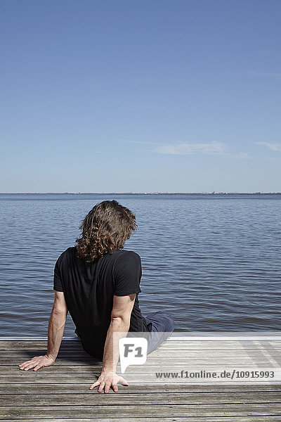 Back view of man sitting on jetty