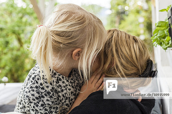 Blondes kleines Mädchen  das seine Mutter küsst.