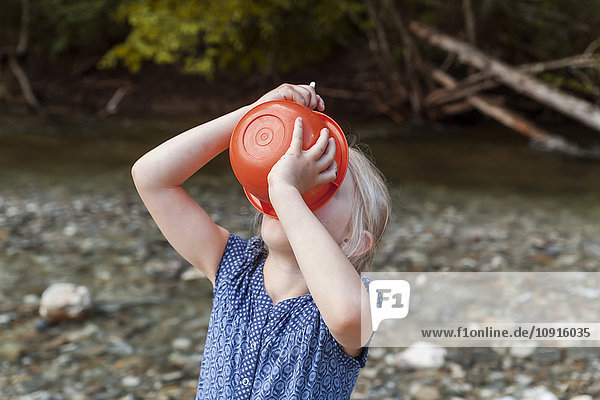 Blond girl drinking from plastic bowl