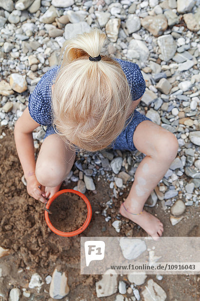 Blondes kleines Mädchen spielt mit Sand in der Natur