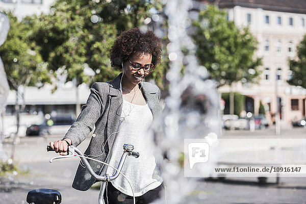 Porträt einer lächelnden Frau mit Fahrrad Musik hören mit Kopfhörer