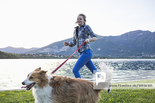 Italien  Lecco  Teenager-Mädchen  das mit ihrem Hund am Seeufer läuft