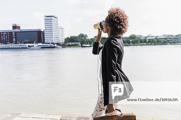 Deutschland  Mannheim  junge Geschäftsfrau beim Kaffeetrinken am Flussufer