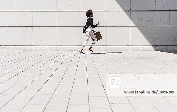 Running businesswoman with smartphone and briefcase