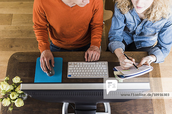 Zwei Kollegen am Schreibtisch mit Computer und Notizblock