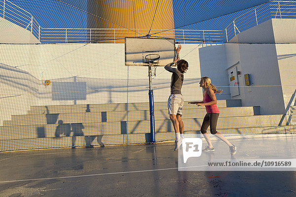 Ein Paar spielt Basketball auf dem Deck eines Kreuzfahrtschiffes.