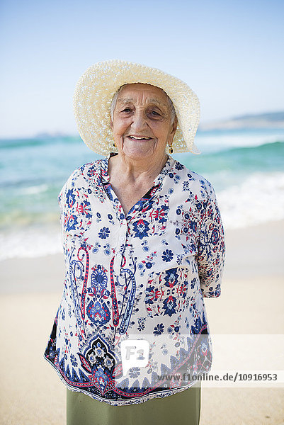 Porträt einer lächelnden Seniorin am Strand stehend