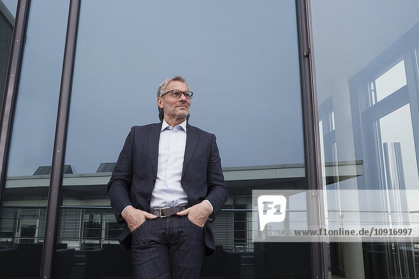 Successful businessman standing on office terrace looking pleased