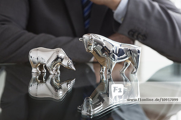 Businessman observing stock market  bull and bear figurines