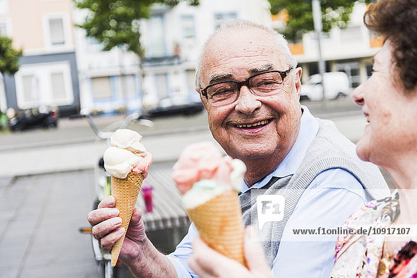 Portrait of happy senior man with ice cream cone looking at his wife