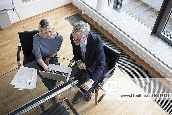 Businessman and woman working together in office using laptop