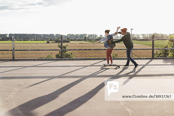 Junges Paar mit Skateboard auf Parkebene