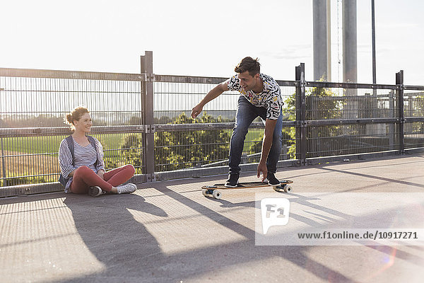 Junges Paar mit Skateboard auf Parkebene