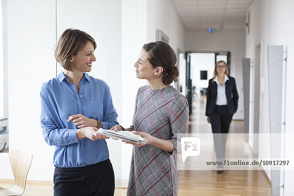 Smiling businesswomen with documents in office hall