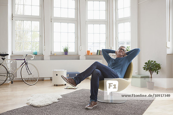 Relaxed mature man at home sitting in chair