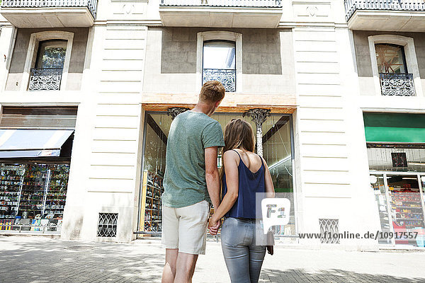 Spanien  Barcelon  Rückansicht eines Paares  das vor einem Gebäude Händchen hält.