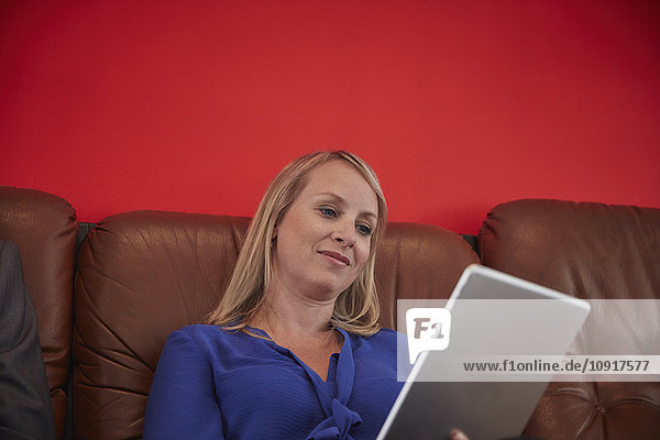 Frau im Büro sitzend mit digitalem Tablett