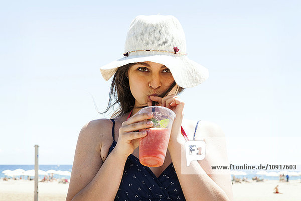 Junge Frau trinkt Cocktail am Strand