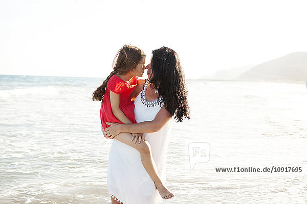 Mutter und kleine Tochter reiben sich die Nasen an der Strandpromenade.