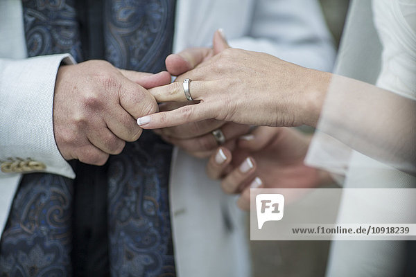Hände von Braut und Bräutigam mit Ehering