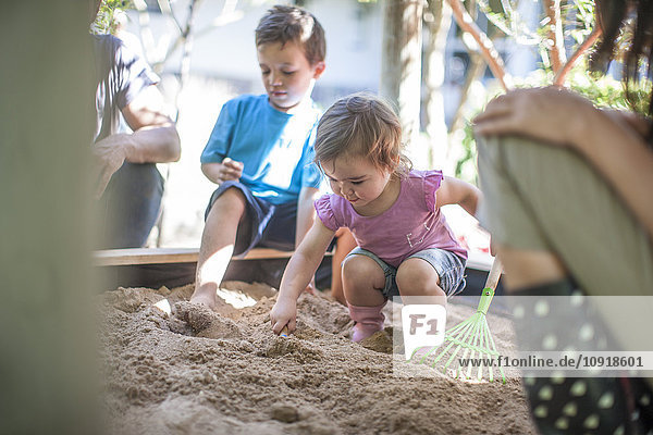 Mädchen mit Familie beim Spielen im Sandkasten