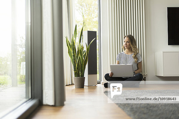 Woman at home sitting on floor with laptop